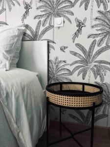 里摩日Limoges Sud-LesCinqSuites-L'Eden - DABNB的一间卧室配有一张床和一张桌子,并拥有棕榈树壁纸