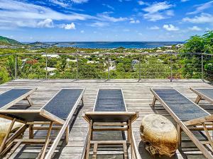 东方湾Casa Del Mar, luxury and magical view of Orient Bay的一个带桌椅的木制甲板和大海