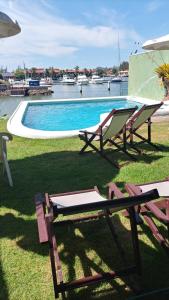 布希奥斯Morada do Canal Suites em Búzios的一个带两把草坪椅和桌子的游泳池