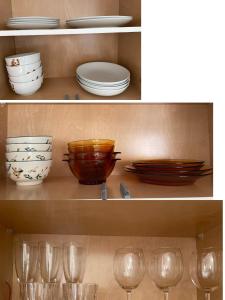 温哥华Brand new 1Queenbed family suite near UBC的架子上两张盘子、碗和玻璃的照片