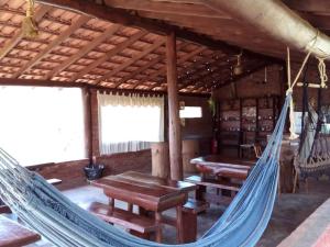 布埃诺布兰当Pousada e Camping Pé na Trilha的小屋配有一张吊床,设有桌子和长凳