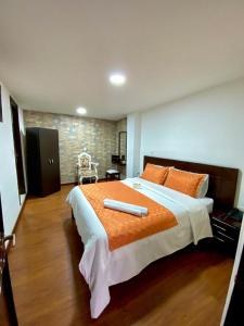 帕斯托Ayenda Hotel Posada Leon的一间卧室配有一张带橙色棉被的大床