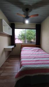托雷斯Casa completa com 2 quartos de casal em Torres的一间卧室配有一张带吊扇和窗户的床。