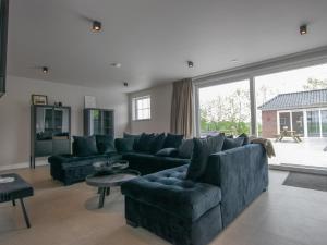 Lage ZwaluweJonkershof的客厅设有蓝色的沙发和大窗户
