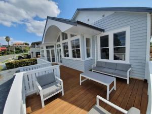陶朗加Tauranga - Big, beautiful Villa on the water!的白色的房子,配有带两把椅子和长凳的甲板