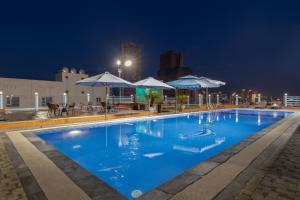 岘港星空酒店的大型蓝色泳池,晚上配有遮阳伞