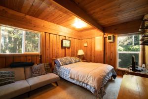 Otter RockThe Cedar House的小屋内一间卧室配有一张床和一张沙发