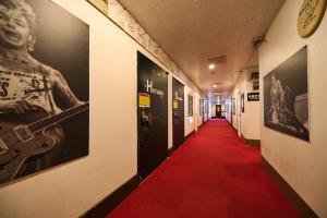 富士河口湖卡米洛特宾馆的一条铺有红地毯的走廊和一条长长的走廊,墙上挂着吉他