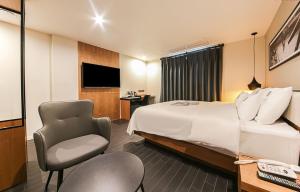 釜山Gray 191 Hotel的配有一张床和一把椅子的酒店客房