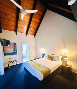 罗托鲁瓦威利苑汽车旅馆的卧室配有一张白色大床和木制天花板