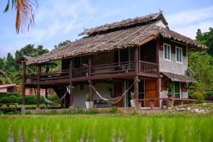Ban Mae La Noiเฮินไต รีสอร์ท แม่ลาน้อย的茅草屋顶和门廊的房子