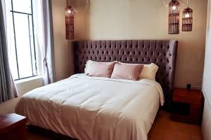 瓜达拉哈拉Real Santuario的卧室配有一张带白色床单和粉红色枕头的大床。