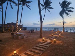 马拉维拉Adique's Resorts的棕榈树海滩上的一组蜡烛