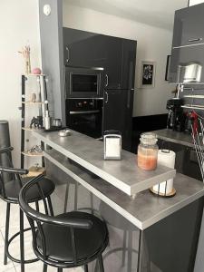 奥祖瓦尔-拉费里耶尔Appartement - Chic et Cosy à 30 minutes de Paris et 25 minutes de Disney的厨房配有带2把椅子的柜台和台面