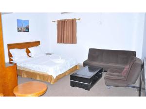 朱巴Lamerinn Hotel Juba的一间卧室配有一张床、一把椅子和一张沙发