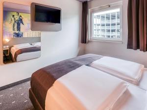 斯图加特斯图加特-瓦和因根住宿加早餐酒店的酒店客房设有一张床和墙上的电视