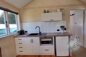 怀蒂昂格Kanuka Cottage的厨房配有白色橱柜、水槽和炉灶。