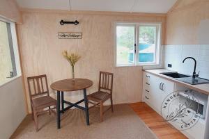 怀蒂昂格Kanuka Cottage的厨房配有桌子、两把椅子和水槽