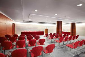 安道尔城Sercotel Delfos Andorra的一间会议室,配有红色的桌椅和讲台