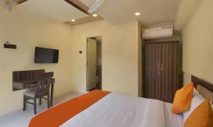 浦那FabHotel Gargi Suites Shivajinagar的一间卧室配有一张床、一张书桌和一台电视