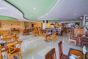 登巴萨Grand Santhi Hotel的一间带木桌椅的餐厅和一间酒吧