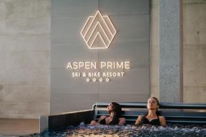 格武霍瓦济Aspen Prime Ski & Bike Resort - basen, sauna, jacuzzi, siłownia w cenie pobytu的两个女人坐在一个椅子上,在一块标志前面