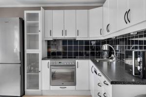 特罗姆瑟The Urban Cityscape的厨房配有白色橱柜和冰箱。