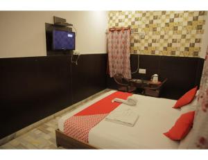 焦特布尔HOTEL SANDS INN, Jodhpur的一间卧室配有一张带电视和桌子的床。