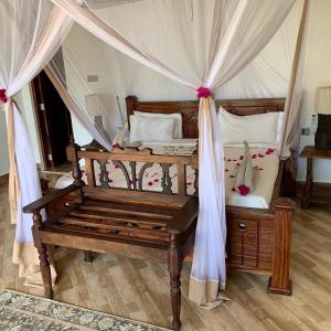 马特姆维Zi Villa Garden Room 1的一间卧室配有一张带长凳的天蓬床
