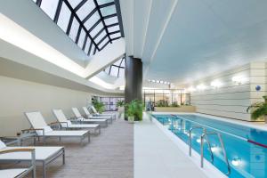 东京东京希尔顿酒店的一个带白色椅子的游泳池和一个游泳池