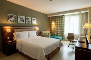 梅里达梅里达希尔顿汉普顿酒店的配有一张床和一把椅子的酒店客房