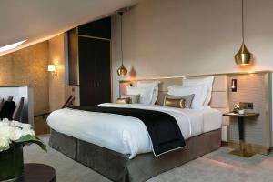 巴黎尼皮斯巴黎希尔顿Curio Collection酒店的卧室配有一张带白色床单和枕头的大床。