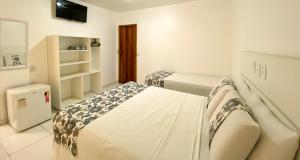塞古罗港Hotel Malibu的白色的客房配有两张床和电视。