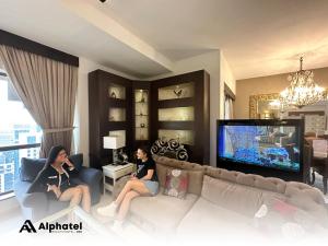 迪拜Alphatel Beach Hostel JBR的两个女人坐在客厅的沙发上