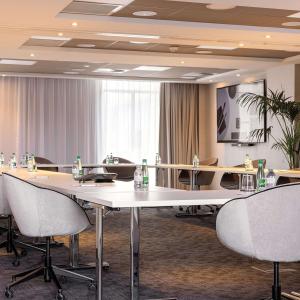 图尔Hilton Garden Inn Tours Centre, France的一间会议室,配有一张白色的大桌子和椅子