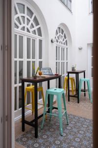 塞维利亚U-Sense For You Hostel Sevilla的一间设有两张桌子和五颜六色椅子的房间
