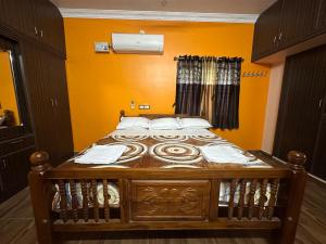 Jothi Cottage -HomeStay的橙色墙壁的木床