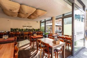 上韦瑟尔DAS WESEL - DEIN HOTEL AM RHEIN的餐厅设有木桌、椅子和窗户。