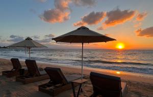 阿特米达Loft Studios的海滩上的一组椅子和遮阳伞,伴随着日落