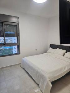 Qiryat YamElegant 3 bedroom Ocean view Condo in Kiryat Yam的白色卧室设有一张大床和窗户
