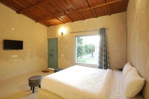BhundsiBrahmaputra cafe and resort的一间卧室设有一张大床和一个窗户。