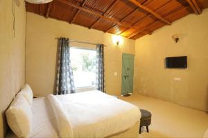 BhundsiBrahmaputra cafe and resort的卧室配有白色的床和窗户。