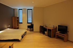 鲁汶博德郝行酒店的一间卧室配有一张床、一张书桌和一台电视