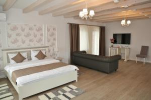 SîrbiDomeniile Panciu Winery & Resort的一间卧室配有一张大床和一张沙发