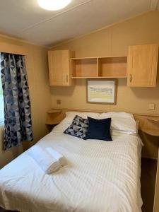 纽基Newquay Bay Porth Caravan - 8 Berth的卧室配有带蓝色枕头的大型白色床