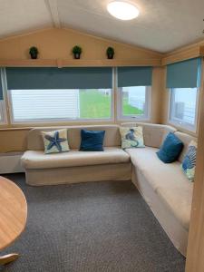 纽基Newquay Bay Porth Caravan - 8 Berth的客厅配有带蓝色枕头的沙发