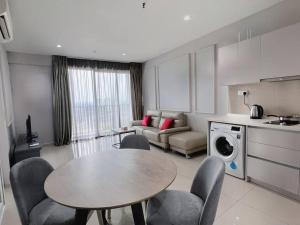 莎阿南Comfy Staycation 4PX with Free Parking, Direct Linked SOGO & Central I-CITY的厨房以及带桌椅的起居室。