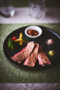 神户結びの小宿 縁的桌子上放着肉和蔬菜的黑盘