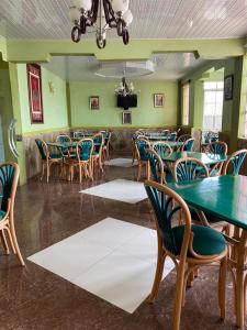 KimanaPenuel Plaza Hotel的一间拥有绿色墙壁和桌椅的用餐室