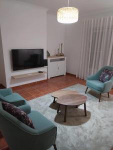 法蒂玛Casa com ALma的客厅配有两把椅子、一张桌子和一台电视